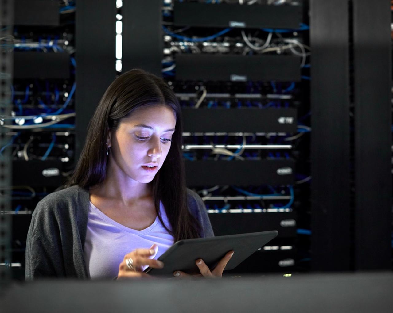 IT professional reviewing a tablet in a data center